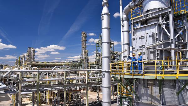 Two people stand in an oil refinery