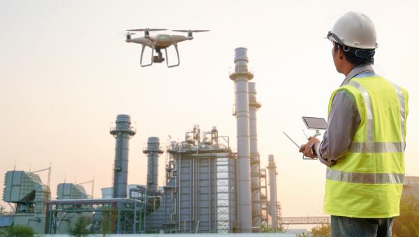 A drone hovers in front of a refinery