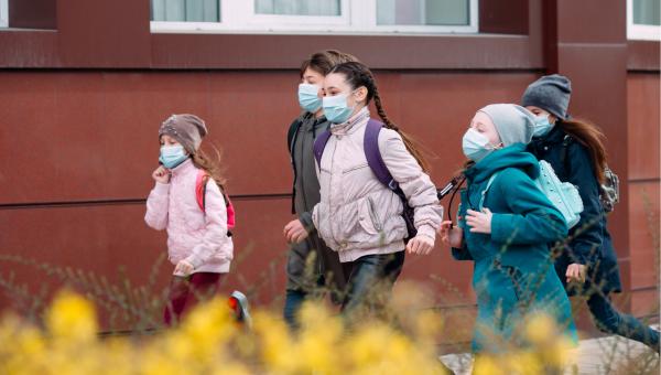 kids walk down street wearing masks