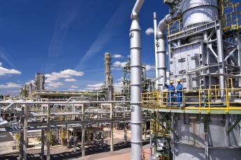 Two people stand in an oil refinery