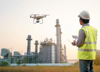 A drone hovers in front of a refinery