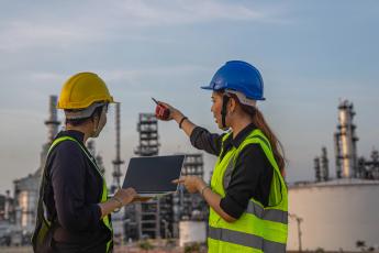 Two refinery workers in front of a plant