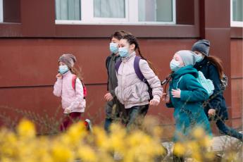 kids walk down street wearing masks